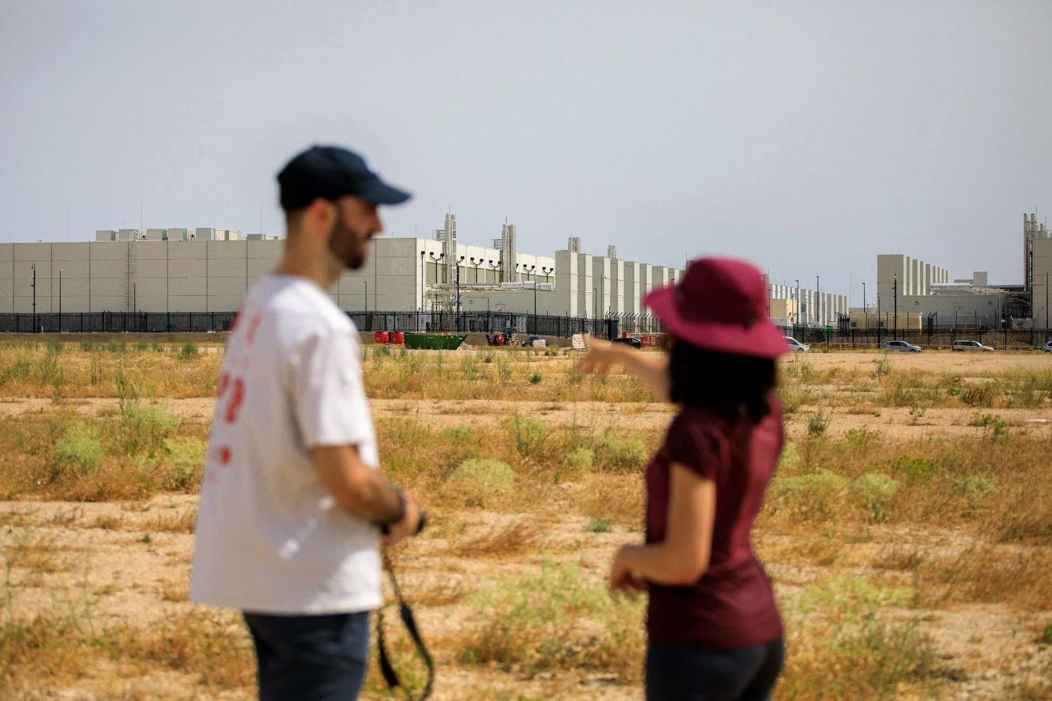 Cristina García, from the ‘No es sequía es saqueo’ collective, and researcher Enol Nieto talk in front of the AWS complex in Villanueva de Gállego (Zaragoza), one of the company’s three data centers already operational in Aragón. / José A. López