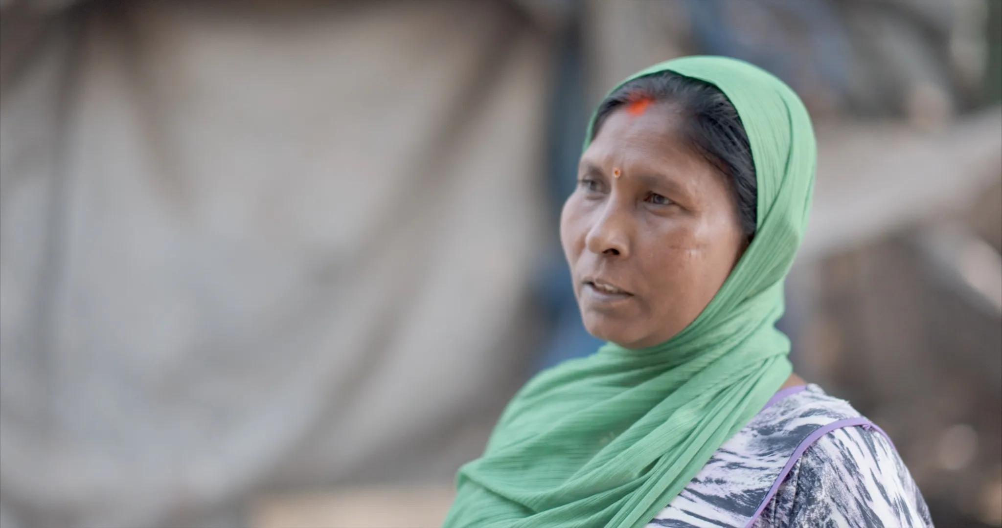 Shrimati Chauhan stands outside her makeshift home in Jai Bhim Nagar, Hiranandani Gardens, where she has lived since her family was evicted from their 30-year-old home in June 2024.