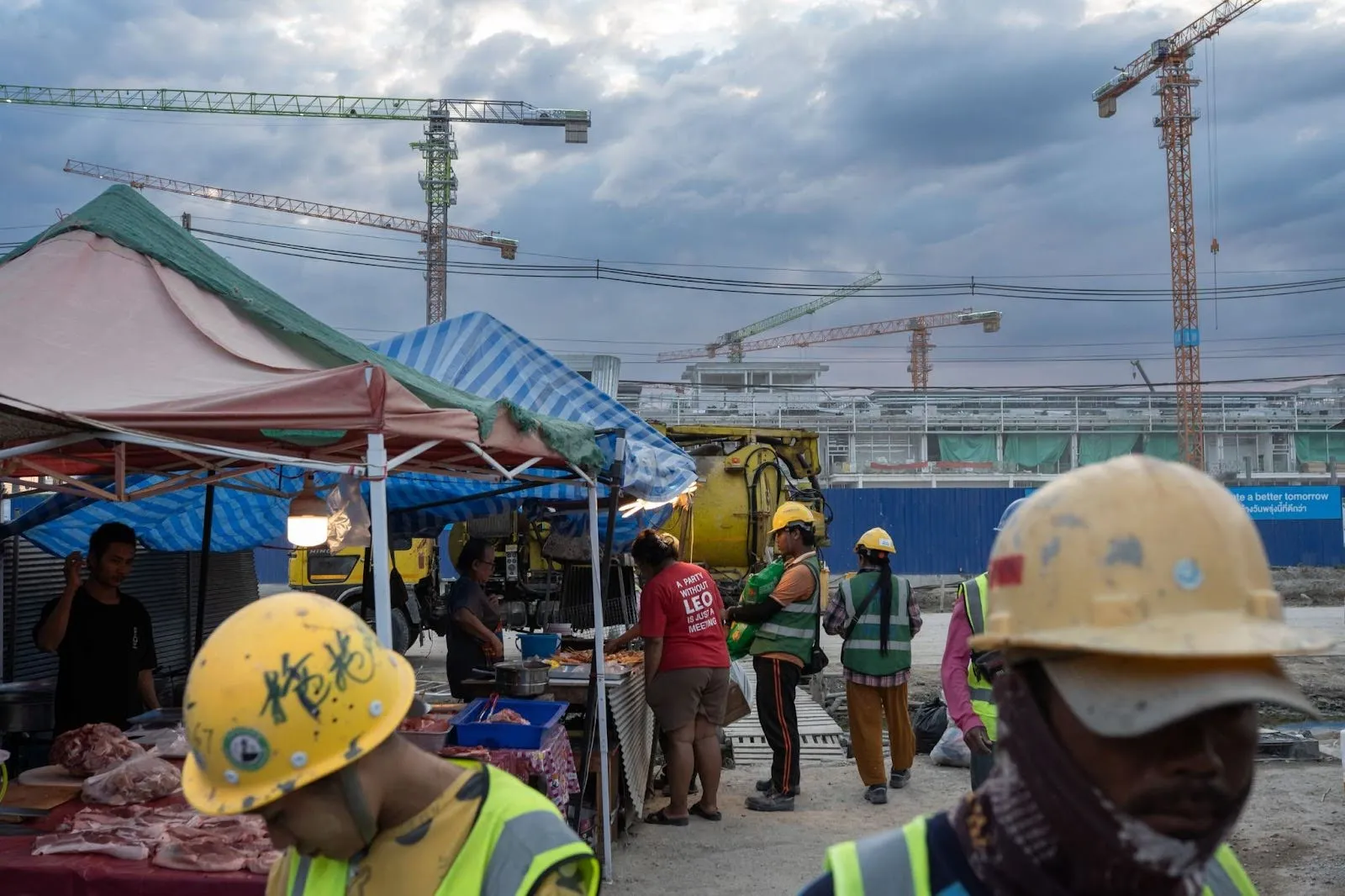 Construction workers building the 200 MW QHI01 data center in Khlong Tamru subdistrict, Chonburi province, Thailand, buy food at a market after finishing work on Feb. 3, 2026.