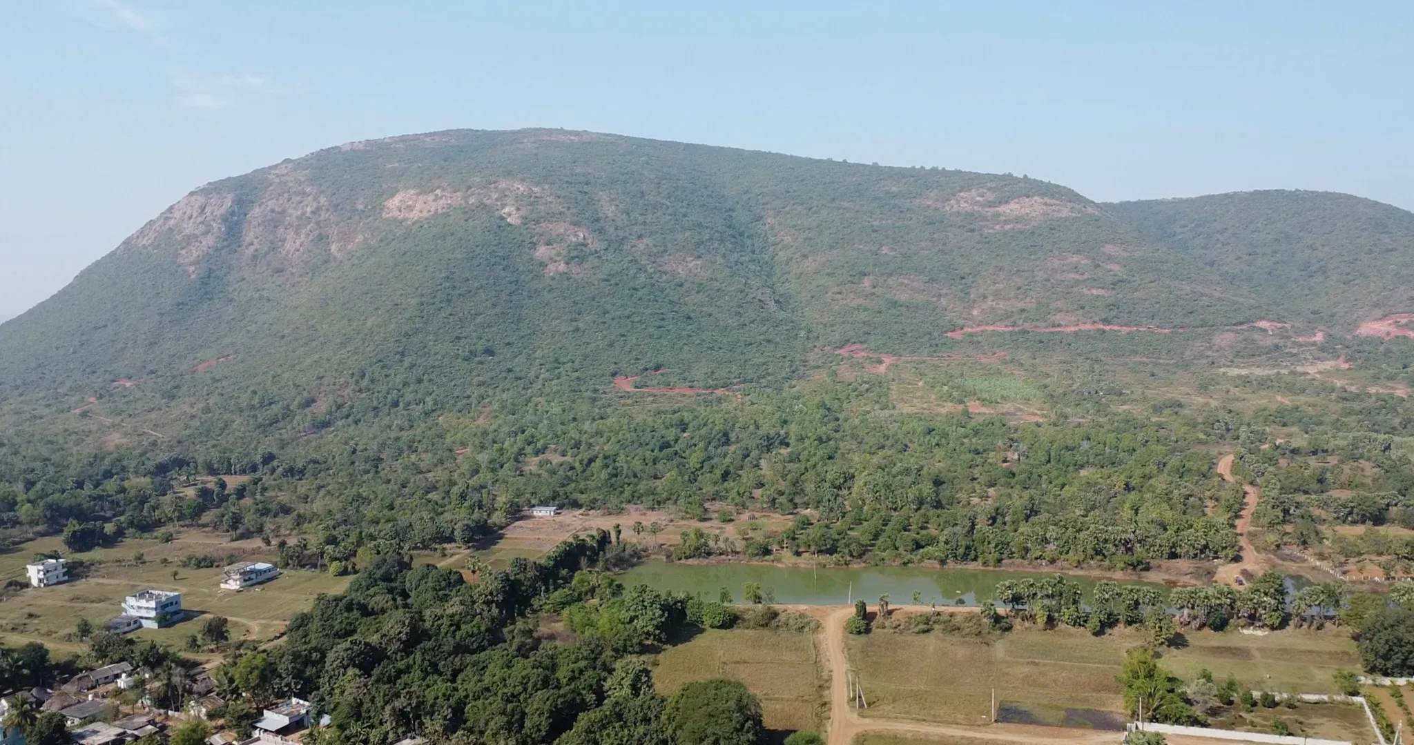 (Aerial view) Chukka Konda hill overlooks houses and agricultural fields at Tarluvada village near Visakhapatnam, where the government is acquiring 200 acres of land for Google's 1 GW data center. An underconstruction road can be seen on the hill, which residents say is being built to facilitate data center construction.